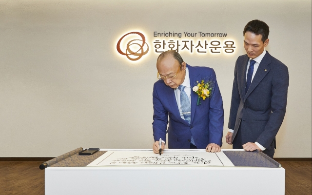 Hanwha Group Chairman Kim Seung-youn (left) visits Hanwha Asset Management headquarters in Yeouido, Seoul, to encourage employees and writes in the guest book on Tuesday. (Hanwha Asset Management)